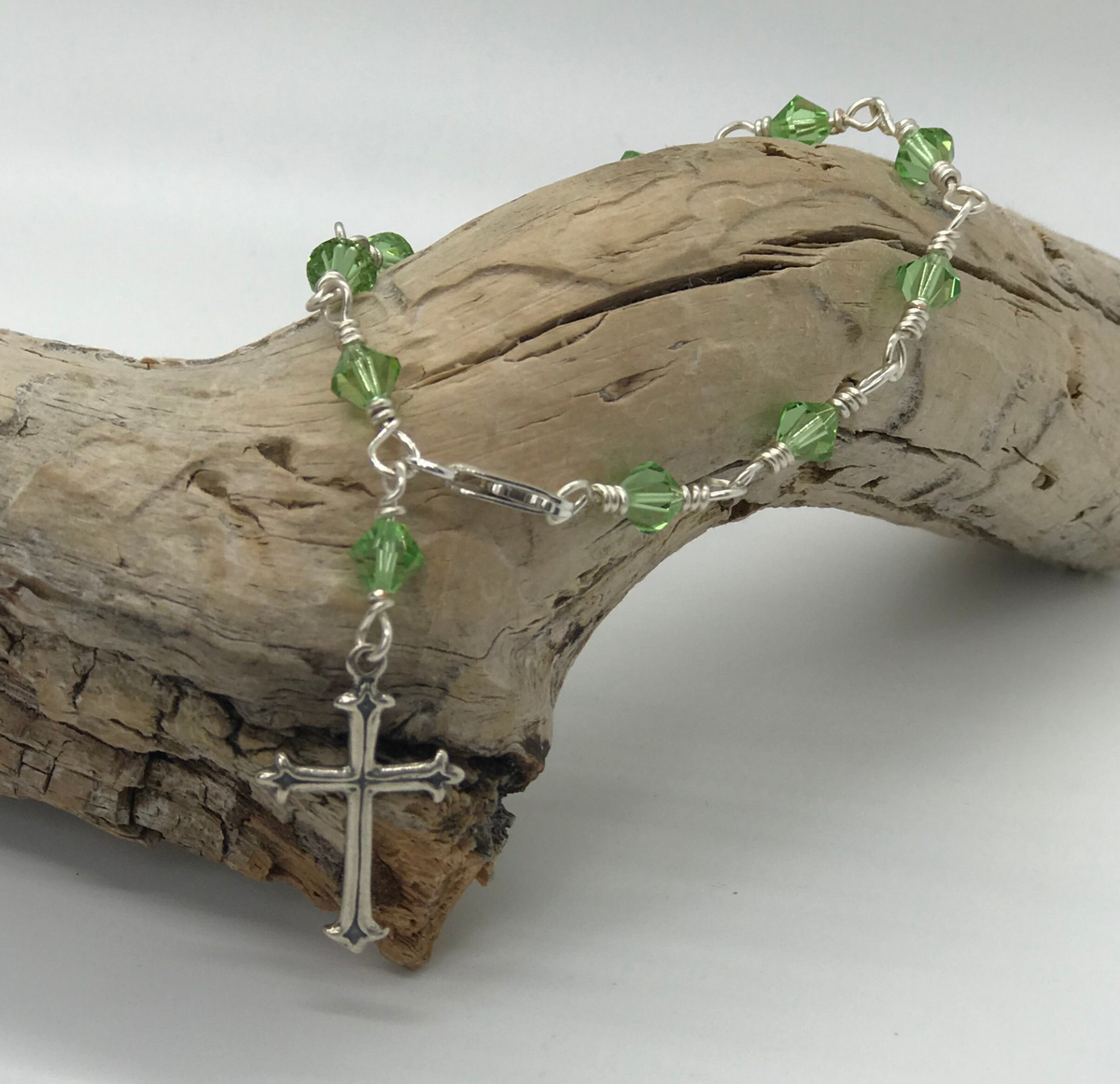 Peridot green crystal one-decade rosary bracelet with cross charm on driftwood