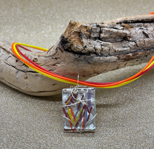 Colorful fused glass pendant necklace on driftwood