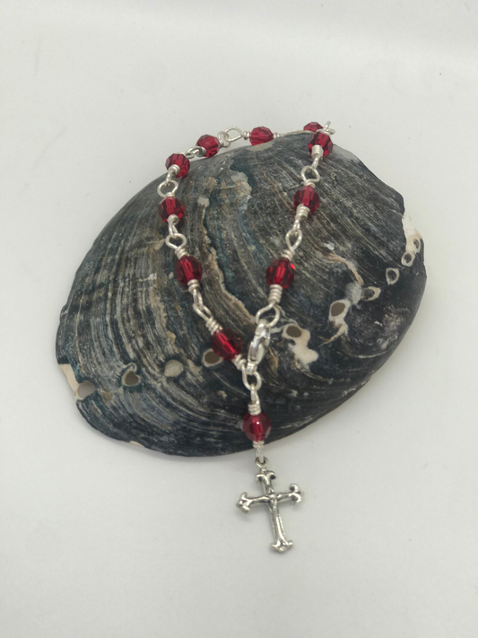 Deep burgundy crystal one-decade rosary bracelet with cross charm on dark shell