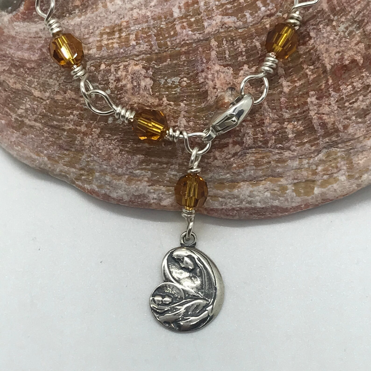 Detail view of golden amber crystal bracelet with Madonna charm and clasp